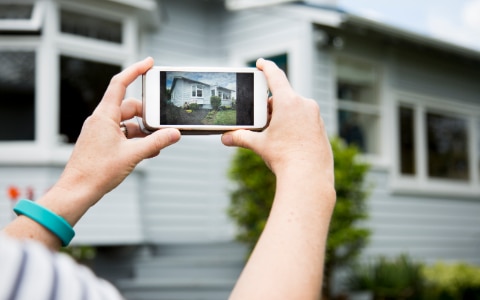 女人用智能手机拍房子的照片