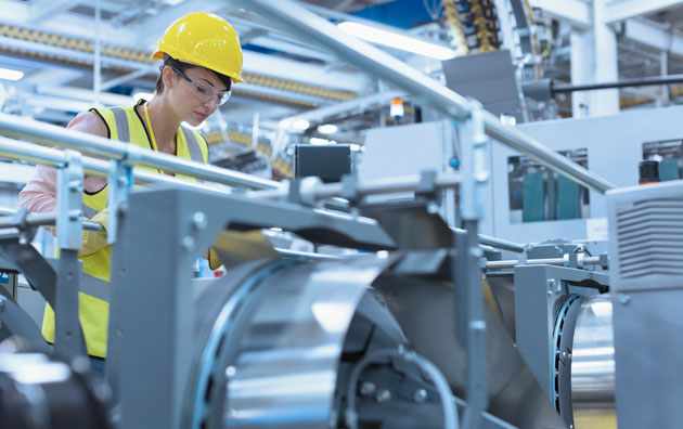 woman checking manufacturing equipment to replace