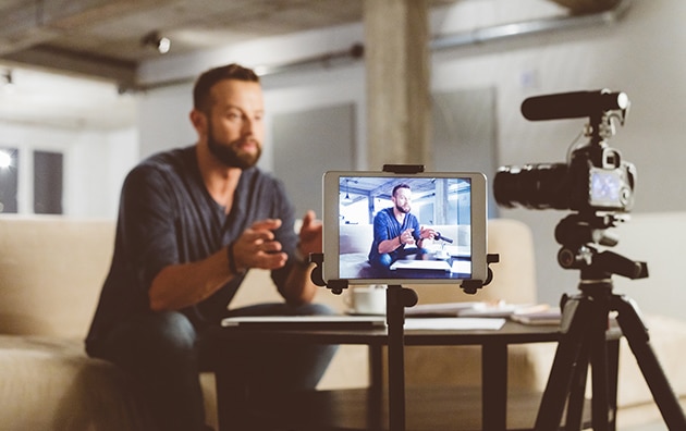 一名男子坐在摄像机前观看在线视频，在COVID-19期间让你的小企业虚拟
