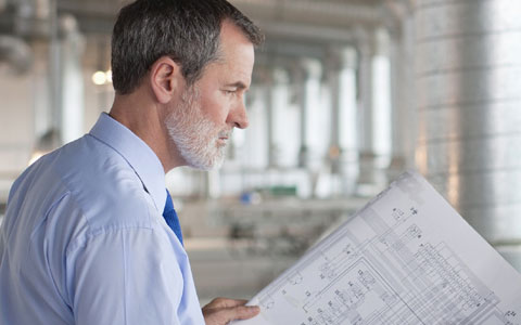 man looking at building design plans, 6 ways to help protect your design firm from professional liability claims
