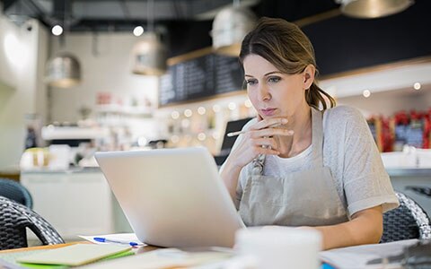 Image of woman in her business looking at a laptop studiously. How to Protect Your Business From a Lawsuit