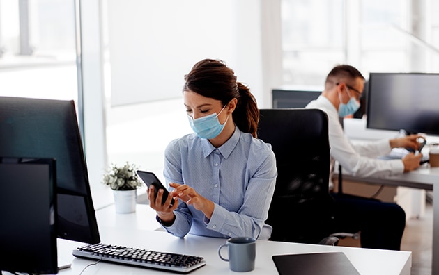 两个人戴着面具在办公室工作。2019冠状病毒病期间，如何让员工在工作场所省钱