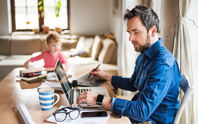 man working from home at table with kid at table, 6 tips for working from home with your kids during the coronavirus