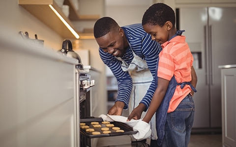 男人和儿子从家里的烤箱里拿出饼干的画面。业主保险包括家用电器吗?