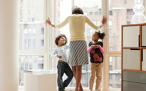 一个女人和孩子们站在公寓的窗户外